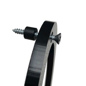 May include: Close-up of a black metal ring with a screw and a rubber washer. The screw is partially inserted into the ring.