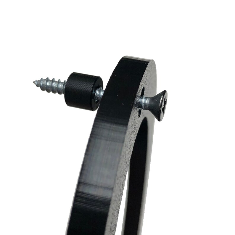 May include: Close-up of a black metal ring with a screw and a rubber washer. The screw is partially inserted into the ring.
