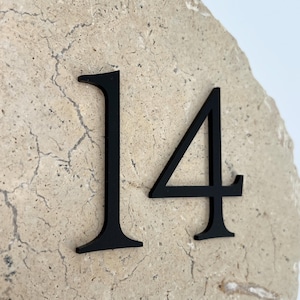 May include: A beige stone with the black number 14 affixed to it. The stone has a rough, textured surface with natural cracks. The numbers are in a modern font.