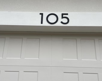 May include: A white garage door with a black house number "105" above it.