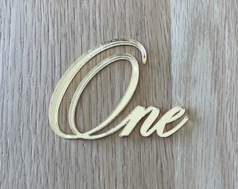 May include: Gold mirrored acrylic 'One' cutout, ideal for a first birthday party or other special occasion.