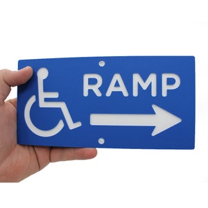 May include: Blue sign with white lettering and a wheelchair symbol. The sign reads "RAMP" with a white arrow pointing to the right.