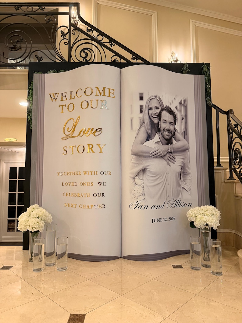 K&ouml;nnte beinhalten: Ein gro&szlig;er, buchf&ouml;rmiger Veranstaltungs-Hintergrund mit dem goldenen Text WELCOME TO OUR Love STORY, TOGETHER WITH OUR LOVED ONES WE CELEBRATE OUR NEXT CHAPTER, einem Schwarz-Wei&szlig;-Foto eines Paares und dem Text Ian and Allison JUNE 12, 2026.