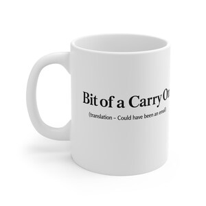 May include: A white ceramic mug featuring the black printed text Bit of a Carry On followed by the smaller parenthetical text translation - Could have been an email. The mug has a standard curved handle and a smooth, cylindrical body design.