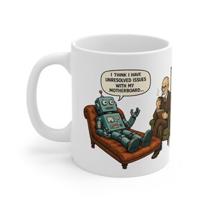 May include: A white ceramic mug featuring a cartoon illustration of a blue robot lying on a brown leather couch, talking to a man in a suit holding a pipe. A speech bubble above the robot contains the text: I THINK I HAVE UNRESOLVED ISSUES WITH MY MOTHERBOARD.