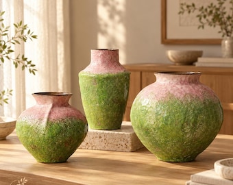Pode incluir: Três vasos de cerâmica com acabamento texturizado, apresentando um design degradê que transita de um rosa suave no topo para um verde vibrante na base. Cada vaso tem uma forma distinta, incluindo uma arredondada, uma alta e uma larga.