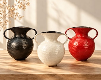 Pode incluir: Três vasos de cerâmica com duas alças cada, apresentando uma superfície texturizada e martelada. Os vasos são pretos, brancos e vermelhos, e cada um tem uma borda larga e alargada. O texto LuaVaseDecor é visível no canto inferior esquerdo.