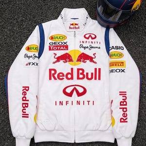 May include: A white zip-up jacket featuring Red Bull branding, two red bulls, and logos for Infiniti, Geox, Total, Pepe Jeans, Casio, and Pirelli. The jacket has blue shoulder accents and is displayed alongside a dark blue and red racing helmet.