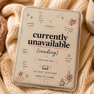 May include: A clear e-reader case featuring a cream-colored insert with black text that reads currently unavailable (reading), status, just five minutes, mentally in a book, not available for reality, page > people, check back later, one more chapter, and DO NOT DISTURB unless it's snacks.