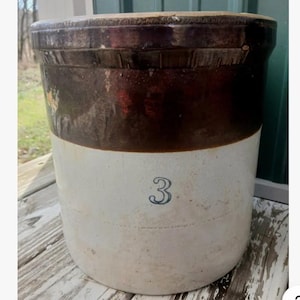 May include: A cylindrical stoneware crock featuring a two-tone design with a dark brown glazed upper section and a light beige lower section. The number 3 is printed in a dark blue color on the front center of the beige portion of the vessel.