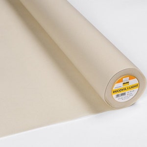 Puede incluir: Un rollo de entretela fusible beige Decovil Light para proyectos de manualidades y costura. La etiqueta dice "Decovil Light 45cm x 1m 20g/m2 Beige".