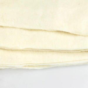 May include: A stack of four white felt squares. The felt is soft and smooth.