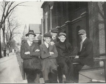 Vieille photo d'hommes assis sur une balustrade portant des costumes et des chapeaux