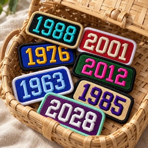 May include: A collection of seven rectangular embroidered patches featuring various years including 1988, 2001, 1976, 2012, 1963, 1985, and 2028. Each patch displays bold, block-style numbers in contrasting colors with distinct stitched borders.