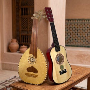 May include: A light-coloured wooden lute with a pear-shaped body and a dark brown neck alongside a light-coloured wooden acoustic guitar with a dark red back and sides, both featuring circular sound holes with intricate decorative patterns.
