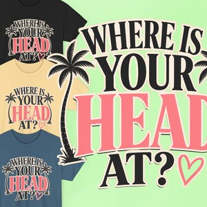 May include: Three short-sleeve t-shirts in black, cream, and blue, each featuring a graphic print with the text WHERE IS YOUR HEAD AT? in black and pink, flanked by two black palm tree silhouettes and a small pink heart outline.