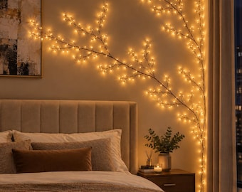 May include: A decorative wall light fixture shaped like a branching tree with thin, dark stems and numerous small, warm-toned LED lights attached to the twigs. The light arrangement extends across the wall, creating a glowing, organic silhouette.
