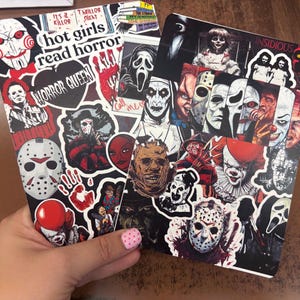May include: Two rectangular items covered in horror-themed stickers featuring iconic movie villains like Jason Voorhees, Pennywise, and Ghostface. Text on the stickers includes "hot girls read horror," "HORROR QUEEN," "It's a killer," and "Thriller Night."
