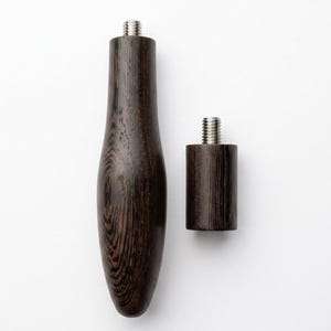 May include: Two dark brown wooden handles with visible wood grain patterns. The longer handle is tapered and rounded at the bottom, while the shorter handle is cylindrical. Both feature a silver-coloured metal threaded bolt at the top end.