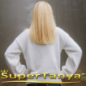 May include: A white fuzzy sweater with long sleeves. The sweater is made of a soft, fluffy material.