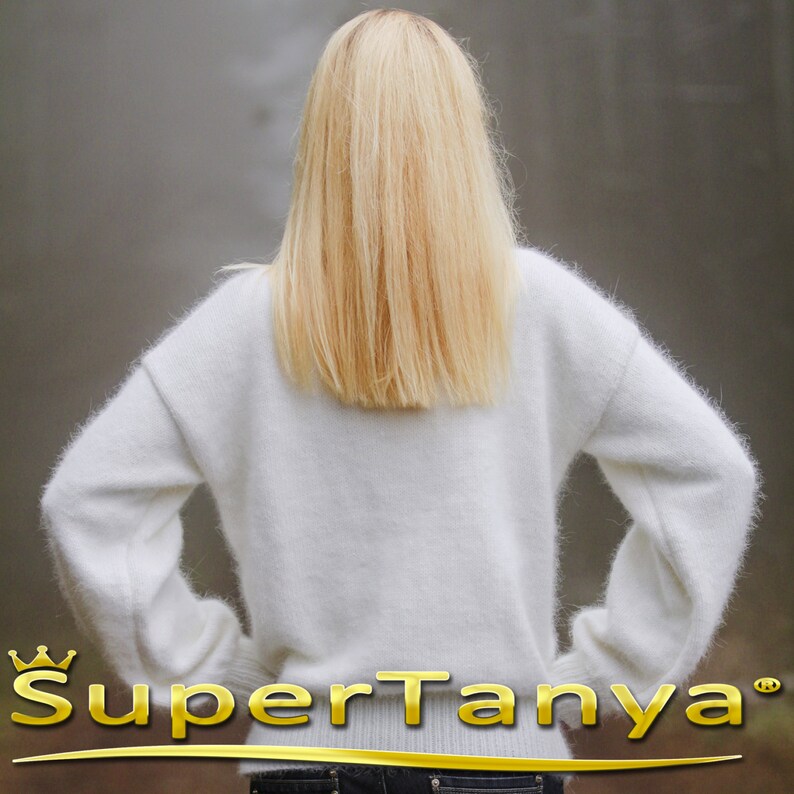 May include: A white fuzzy sweater with long sleeves. The sweater is made of a soft, fluffy material.