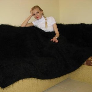 May include: A black fuzzy blanket draped over a couch. The blanket is very soft and fluffy.