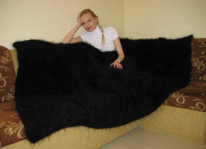 May include: A black fuzzy blanket draped over a couch. The blanket is very soft and fluffy.