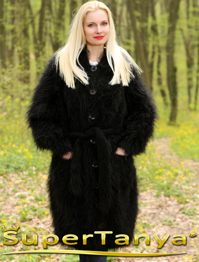 May include: A long black fuzzy cardigan with a belt and button closure. The cardigan is made of a soft, fluffy material and has a relaxed fit.
