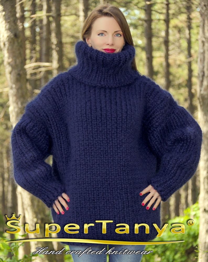 May include: A deep blue, oversized turtleneck sweater made of soft, fuzzy yarn. The sweater has a relaxed fit and long sleeves. The sweater is made by SuperTanya, a company that specializes in hand-crafted knitwear.