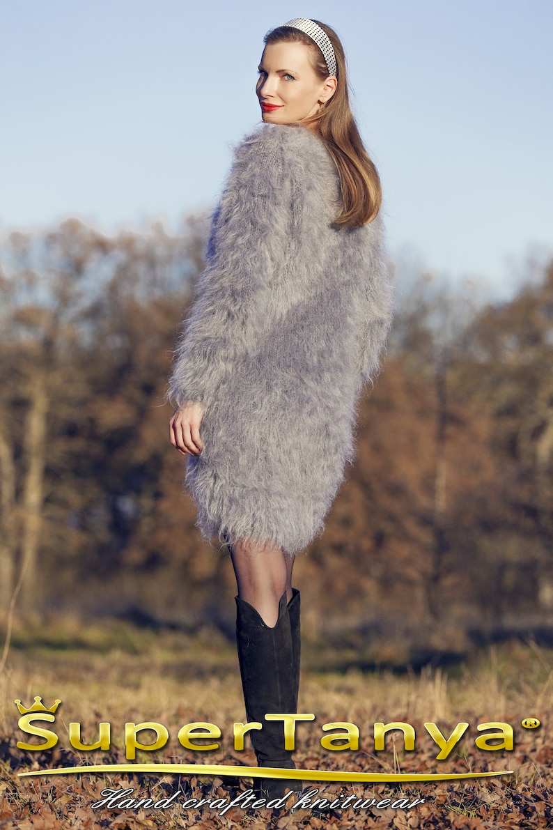 May include: A woman wearing a gray, fuzzy, long-sleeved dress and black boots. The dress has a textured, shaggy appearance. The image includes the text "SuperTanya" and "Hand crafted knitwear".