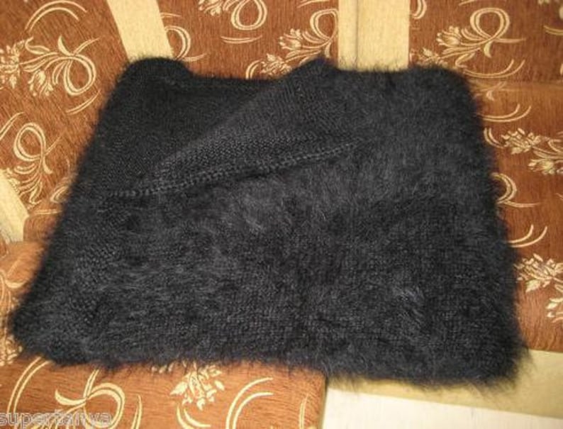 May include: A black fuzzy knit scarf or shawl. The scarf is folded in half and laid on a patterned fabric surface.
