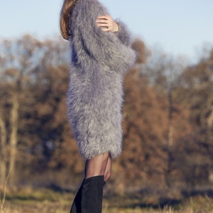 May include: A woman wearing a gray, fuzzy, long-sleeved dress and black knee-high boots. The dress has a soft, textured appearance. The image includes the text "SuperTanya" and "Hand crafted knitwear".