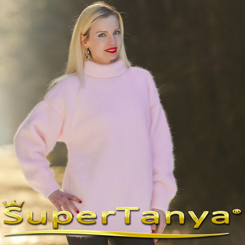 May include: A soft, pale pink, fuzzy turtleneck sweater. The sweater has long sleeves and a relaxed fit.
