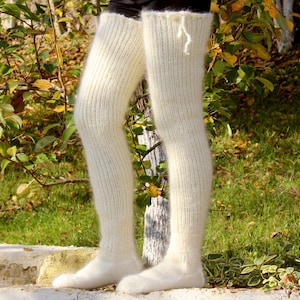 Può includere: Scaldamuscoli a coste color crema. Questi lunghi scaldamuscoli si estendono dal piede alla coscia. Gli scaldamuscoli sono realizzati in un materiale morbido e soffice e sono mostrati all'aperto.