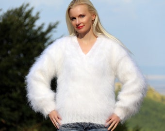 May include: White fuzzy mohair sweater with a v-neck and long sleeves.