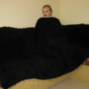 May include: A black fuzzy blanket draped over a couch. The blanket is very soft and fluffy.