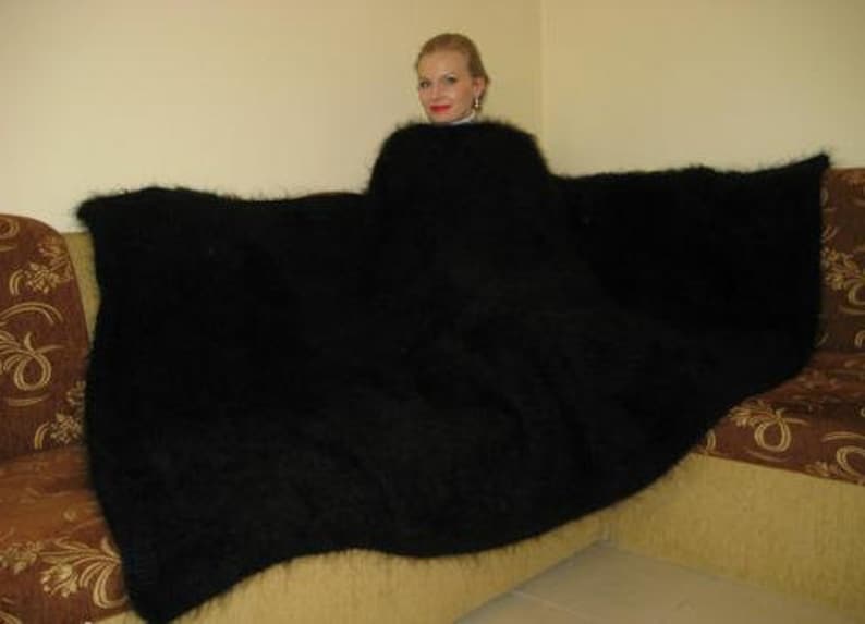 May include: A black fuzzy blanket draped over a couch. The blanket is very soft and fluffy.