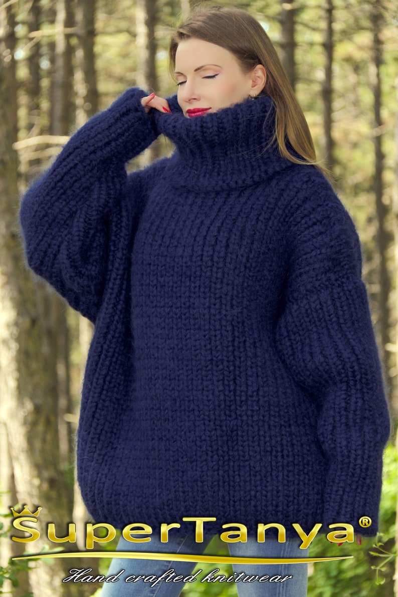 May include: A navy blue oversized turtleneck sweater with a fuzzy texture. The sweater is hand-knitted and has a loose, relaxed fit.