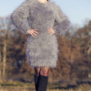 May include: A gray, fuzzy, long-sleeved dress. The dress is knee-length and has a round neckline. The model is wearing black boots. The image includes the text "SuperTanya" and "Hand crafted knitwear".