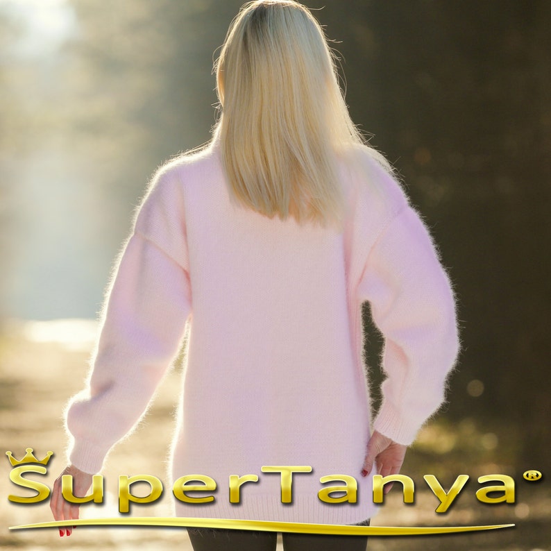 May include: A soft, pink, fuzzy sweater with long sleeves and a loose fit. The sweater is made of a fluffy material and has a relaxed, comfortable look.