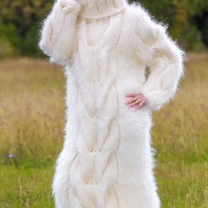 May include: A white fuzzy knit sweater with a high turtleneck and cable knit design. The sweater is long and reaches the ankles.