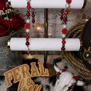 May include: Two beaded lanyards featuring alternating red and silver glitter spheres interspersed with red rose-shaped beads. Each lanyard includes a metal lobster clasp at the end. The beads are arranged in a repeating pattern along a flexible cord.
