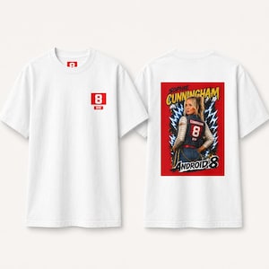 May include: A white short-sleeve t-shirt featuring a small red square logo with the number 8 and RR on the front chest. The back displays a graphic of a person wearing a jersey with the number 8, surrounded by blue lightning and the text Sophie Cunningham Android 8.
