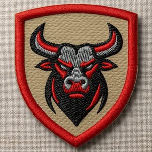 Peut inclure: Un écusson brodé en forme de bouclier représentant une tête de taureau stylisée en fil noir, rouge et gris. Le taureau est centré sur un fond beige, entouré d'une bordure épaisse et rouge vif qui suit le contour de la forme du bouclier.