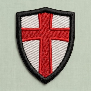 Könnte beinhalten: Ein schildförmiger, bestickter Aufnäher mit einem kräftigen roten Kreuz auf weißem Grund, eingefasst von einem dicken, erhabenen schwarzen Stickrand. Das Design zeigt einen klassischen heraldischen Stil mit klaren Linien und Textur.