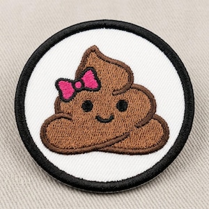 Può includere: Una toppa ricamata circolare che raffigura un personaggio emoji cacca marrone sorridente con un fiocco rosa brillante sulla testa. Il design è posto su uno sfondo bianco ed è incorniciato da un bordo spesso cucito in nero, creando contrasto.
