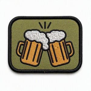 Könnte beinhalten: Ein rechteckiger gestickter Aufnäher mit schwarzem Rand auf olivgrünem Hintergrund. Das Design zeigt zwei gelbe Bierkrüge, die aneinanderstoßen, gefüllt mit goldener Flüssigkeit und gekrönt von dickem, weißem, strukturiertem Schaum mit schwarzen Linien.