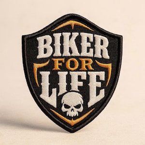 Op de afbeelding: Een schildvormige geborduurde patch met een zwarte achtergrond en een dikke zwarte rand. De tekst BIKER FOR LIFE is geborduurd met wit en goudkleurig garen. Onder de tekst staat een witte schedelafbeelding in het midden van het schild.