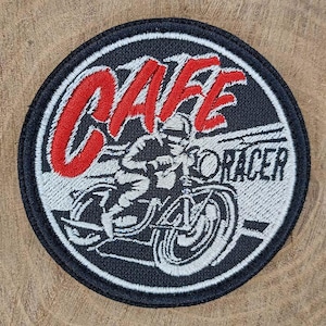 Op de afbeelding: Een ronde geborduurde patch met een zwarte rand. Het ontwerp toont het witte silhouet van een motorfiets met rijder, de rode tekst CAFE en de zwarte tekst RACER. De achtergrond is een mix van zwart en wit garen voor een gedetailleerde afbeelding.