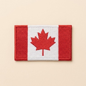 May include: A rectangular embroidered patch featuring the Canadian flag design. The patch has a central white square with a red maple leaf emblem, flanked by two solid red vertical rectangular sections on the left and right sides.